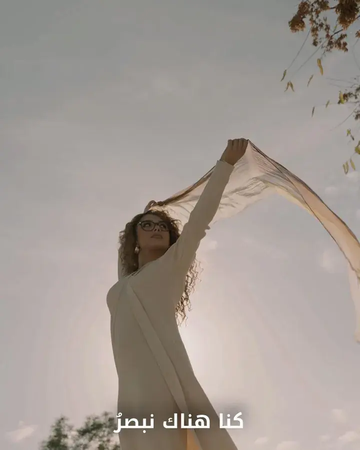A woman holding a sheer scarf up to the wind